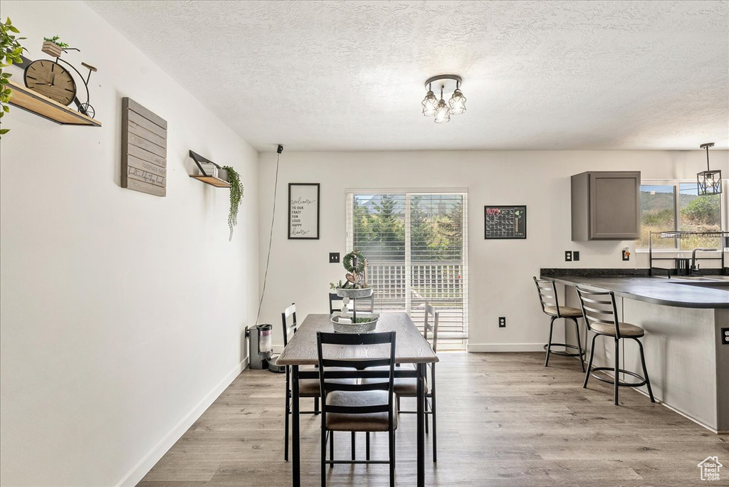 Dining space with healthy amount of natural light, a textured ceiling, a chandelier, and wood finished floors