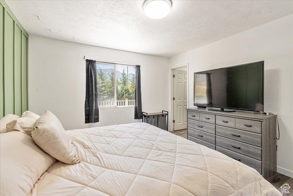 Bedroom with wood finished floors and a textured ceiling