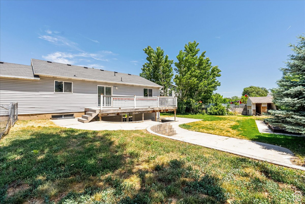 Back of house with a wooden deck, a shed, and a patio