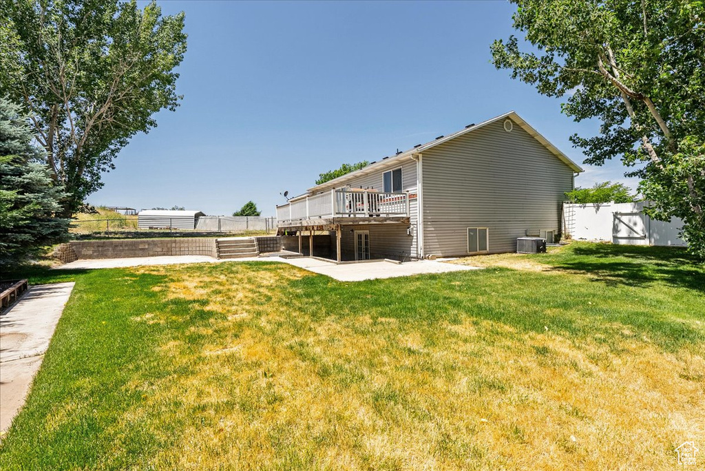 Back of house with a deck and a patio
