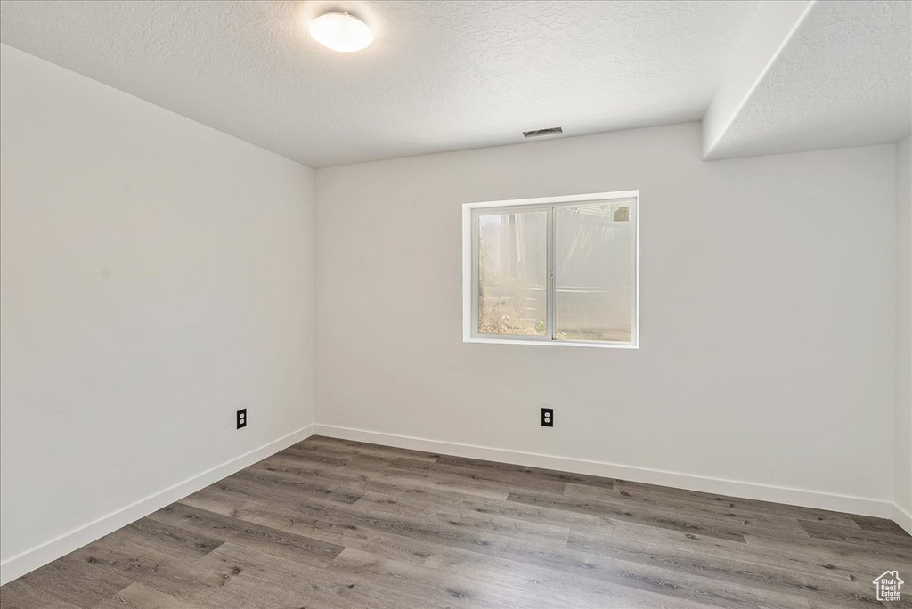 Spare room featuring wood finished floors and a textured ceiling
