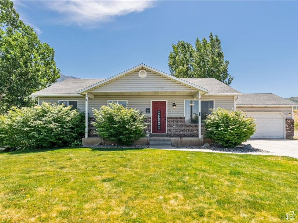 View of front facade with concrete driveway, a garage, a front yard, and brick siding