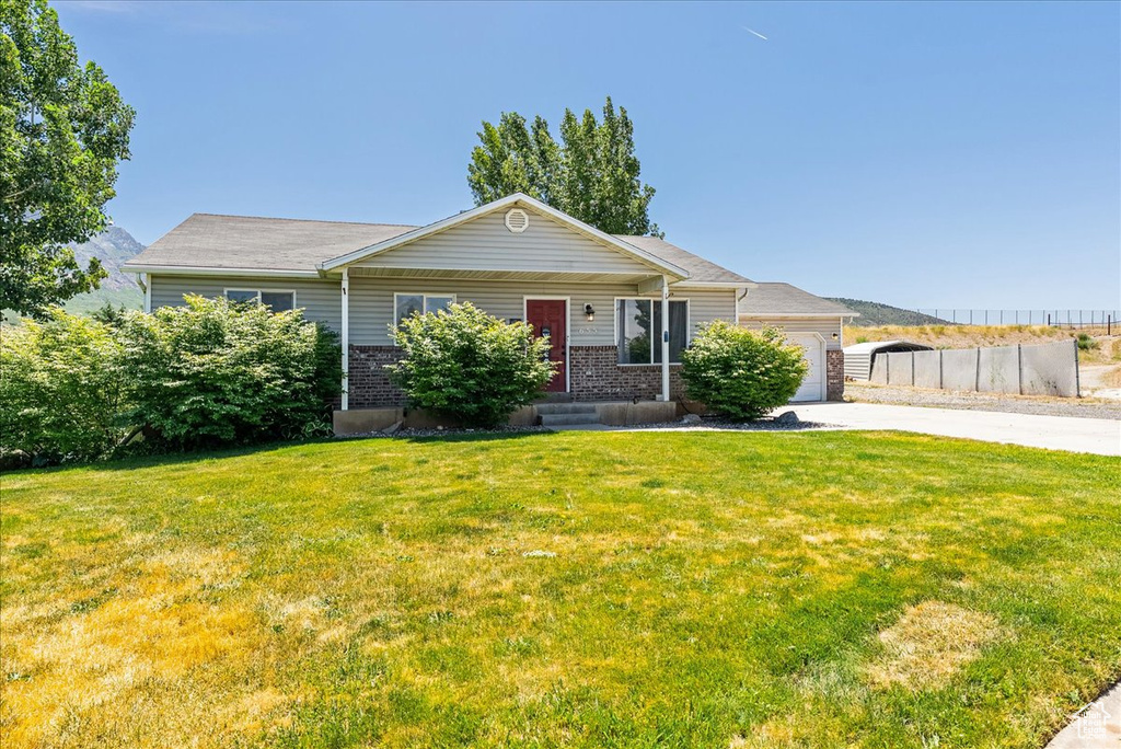 Ranch-style house with concrete driveway, a garage, a front lawn, and brick siding