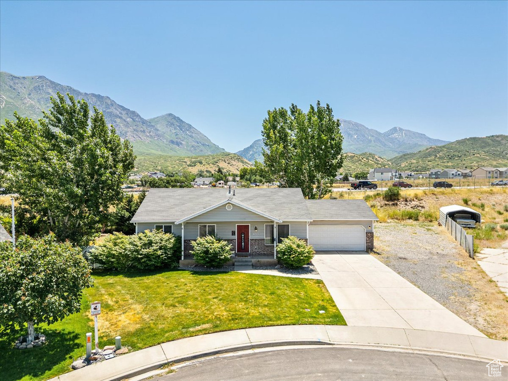 Ranch-style home with an attached garage, a mountain view, driveway, and a front yard