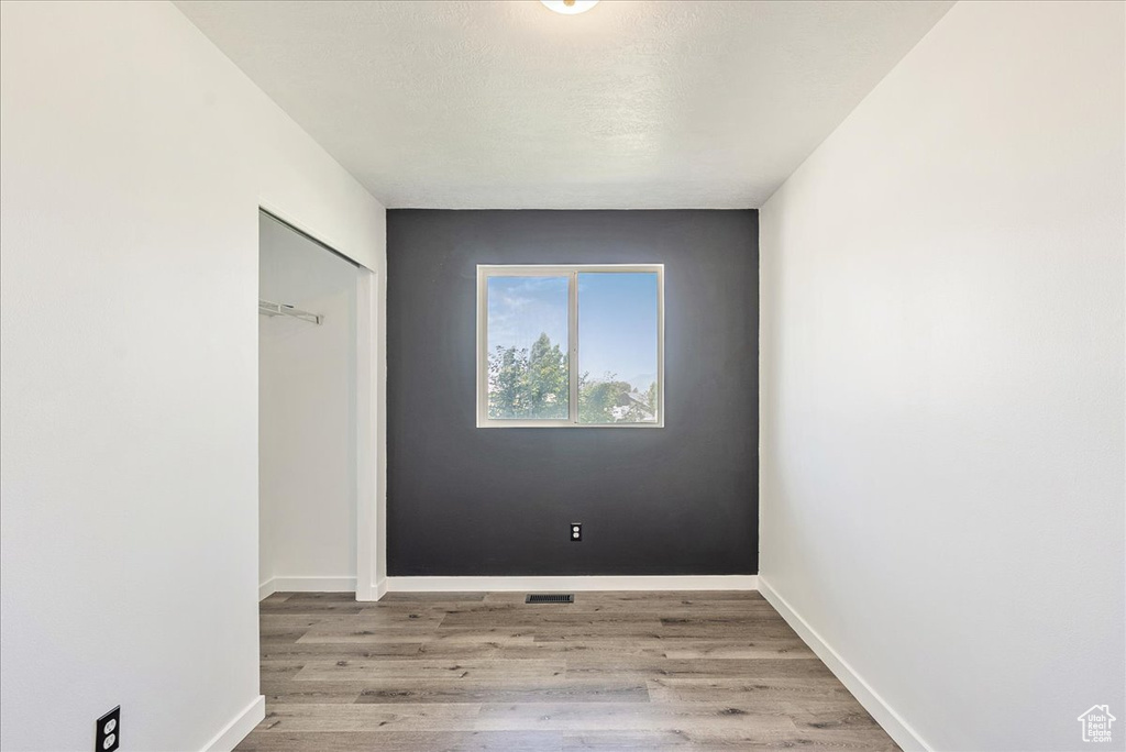 Unfurnished bedroom with wood finished floors and a closet