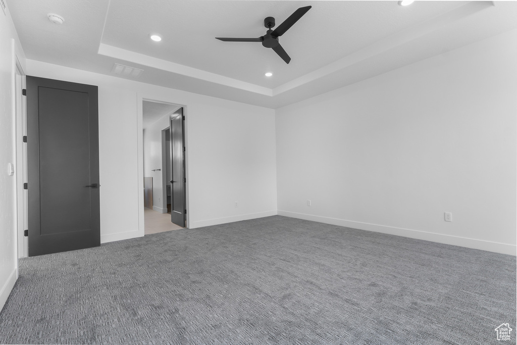 Unfurnished bedroom with a raised ceiling, recessed lighting, carpet floors, a ceiling fan, and ensuite bathroom