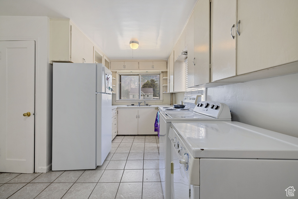 Kitchen with freestanding refrigerator, separate washer and dryer, light tile patterned floors, and light countertops