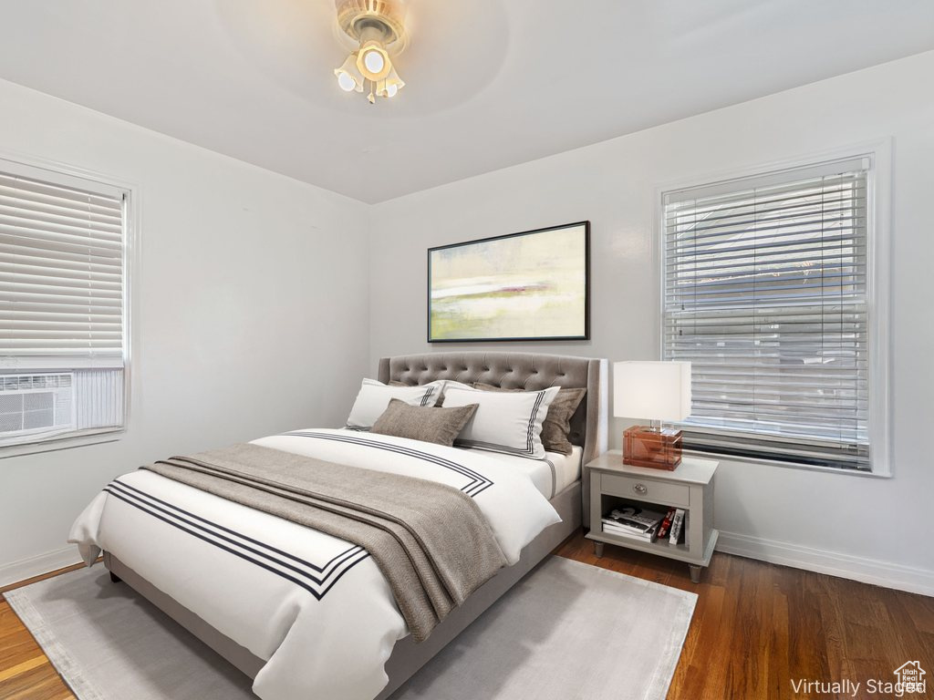 Bedroom with wood finished floors and multiple windows