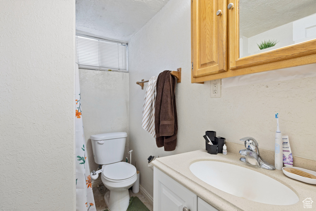 Full bath featuring vanity, curtained shower, and a textured ceiling