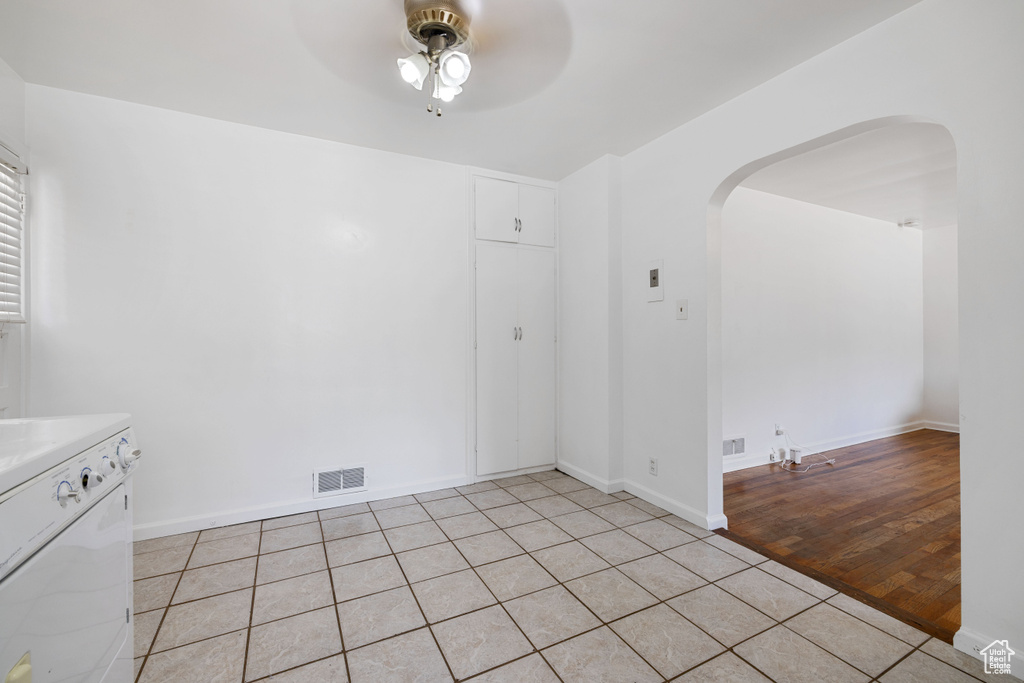 Unfurnished room with arched walkways, a ceiling fan, and light tile patterned flooring