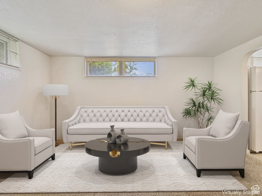 Living room with arched walkways, a textured ceiling, and carpet floors