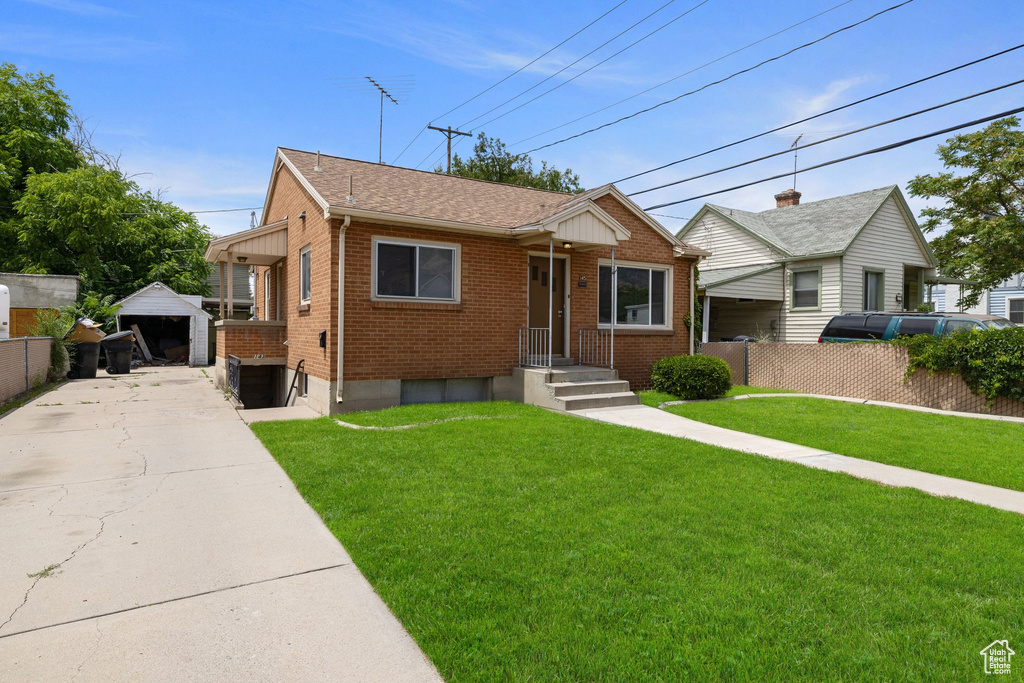 View of front of home with brick siding, an outbuilding, roof with shingles, and a garage