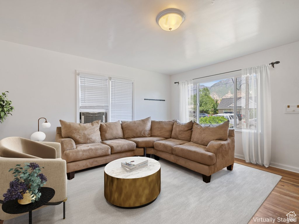 Living area with wood finished floors and cooling unit