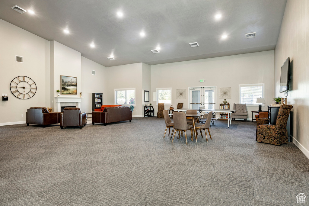 Carpeted dining area with high vaulted ceiling, a fireplace, french doors, and recessed lighting