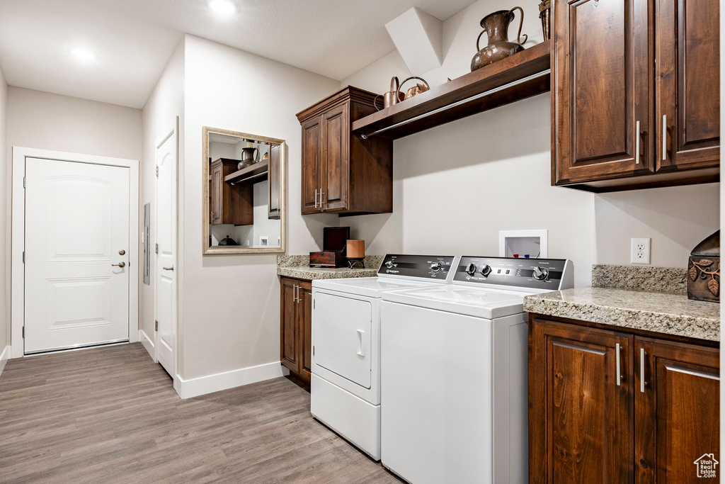 Laundry room featuring cabinet space, light wood-style flooring, washer and dryer, and recessed lighting