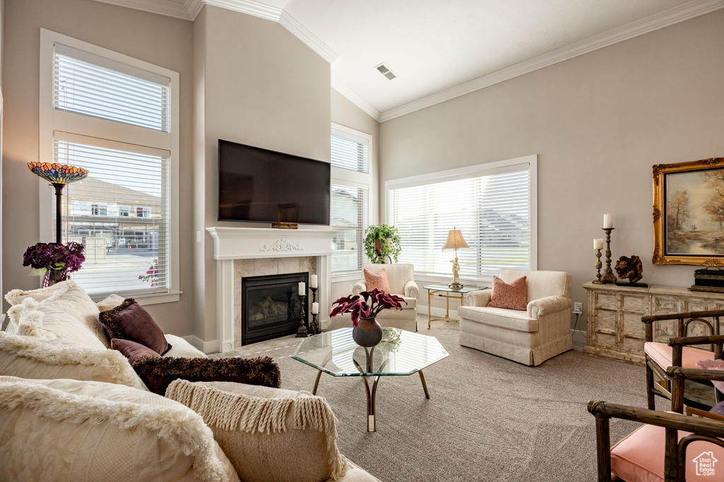Carpeted living area with ornamental molding, a tile fireplace, and high vaulted ceiling