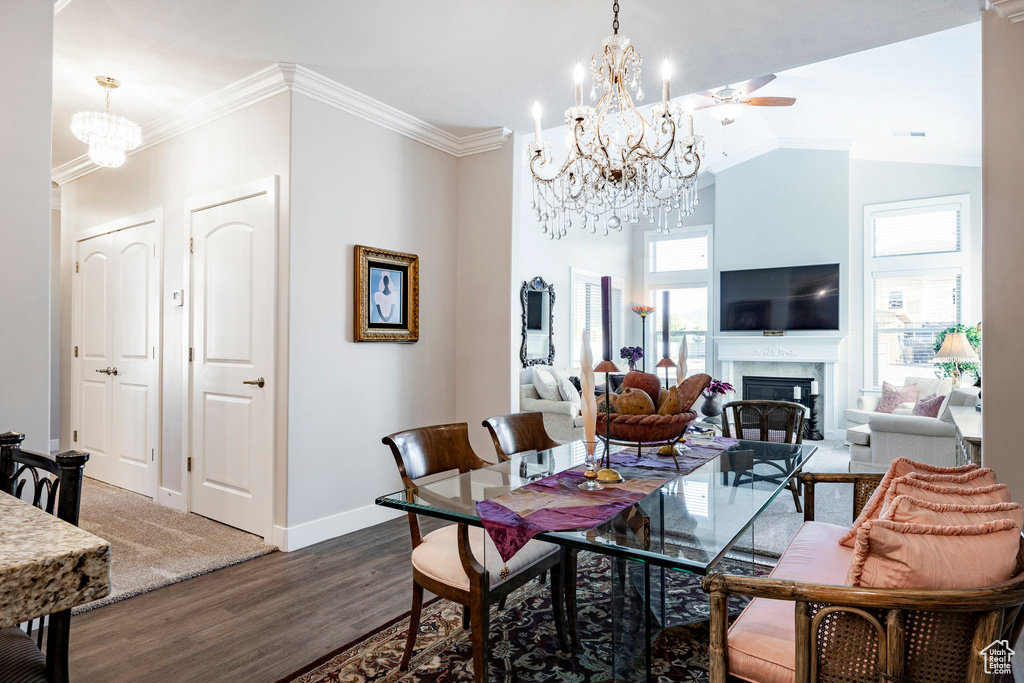 Dining space featuring a chandelier, wood finished floors, a fireplace, ornamental molding, and ceiling fan
