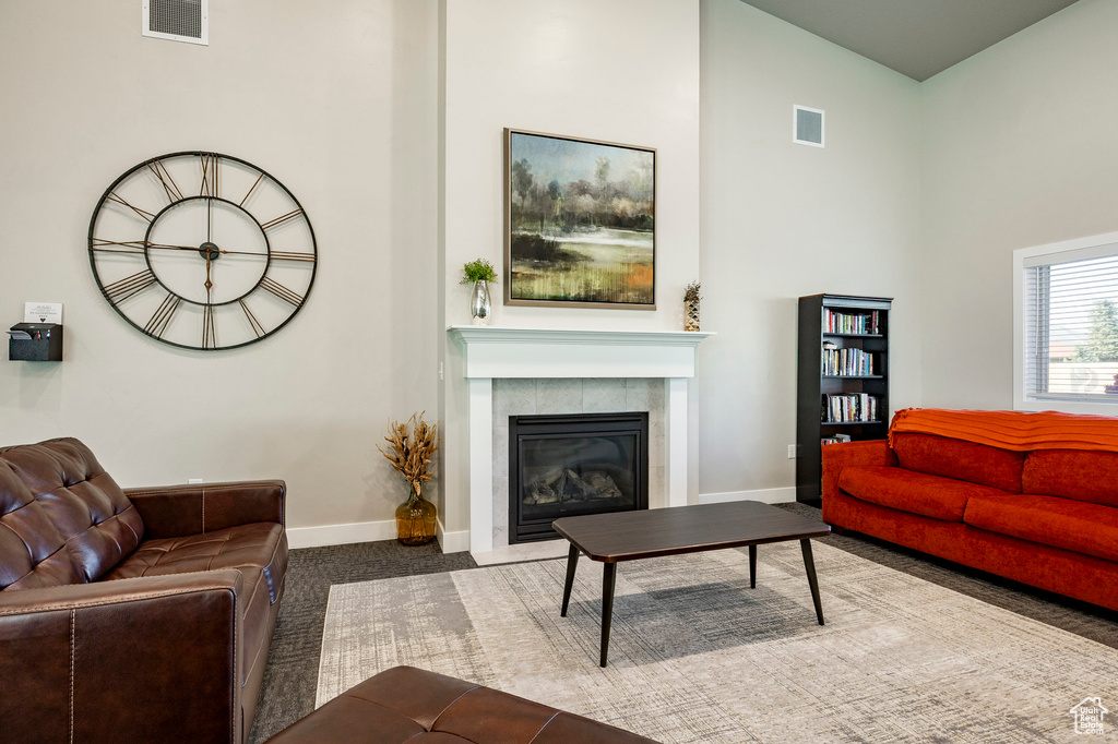 Carpeted living area with a high ceiling and a fireplace