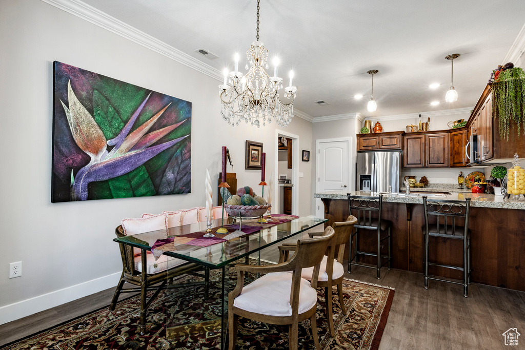 Dining space featuring dark wood finished floors, ornamental molding, and a chandelier