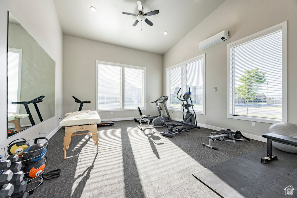 Workout area featuring a wall mounted air conditioner, a ceiling fan, healthy amount of natural light, vaulted ceiling, and carpet flooring