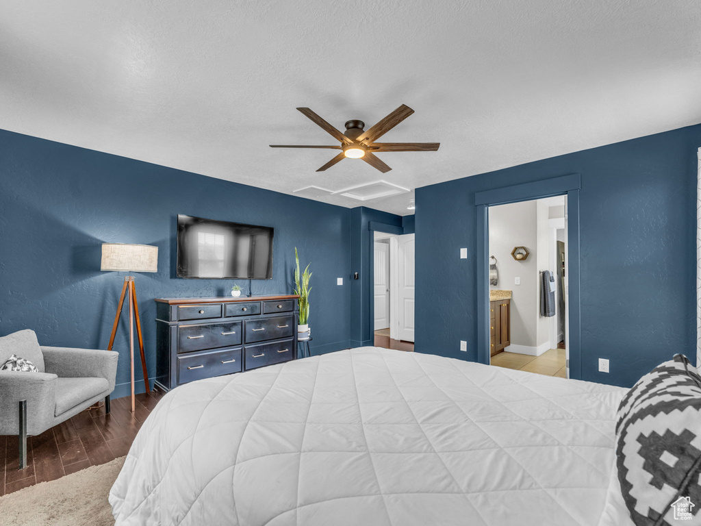 Bedroom with wood finished floors, ensuite bath, and a ceiling fan