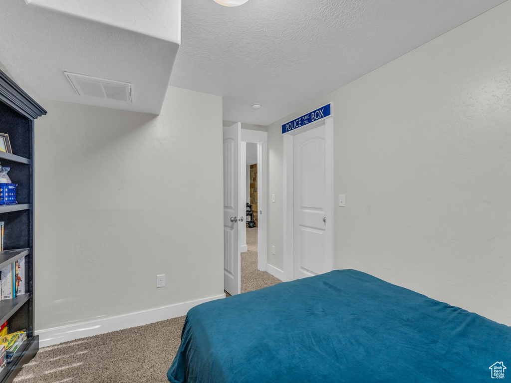 Carpeted bedroom featuring baseboards and a textured ceiling