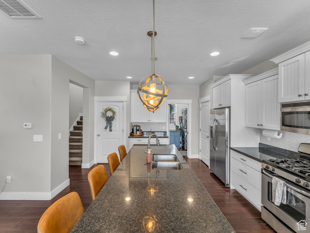 Kitchen with stainless steel appliances, tasteful backsplash, dark wood-type flooring, white cabinetry, and recessed lighting
