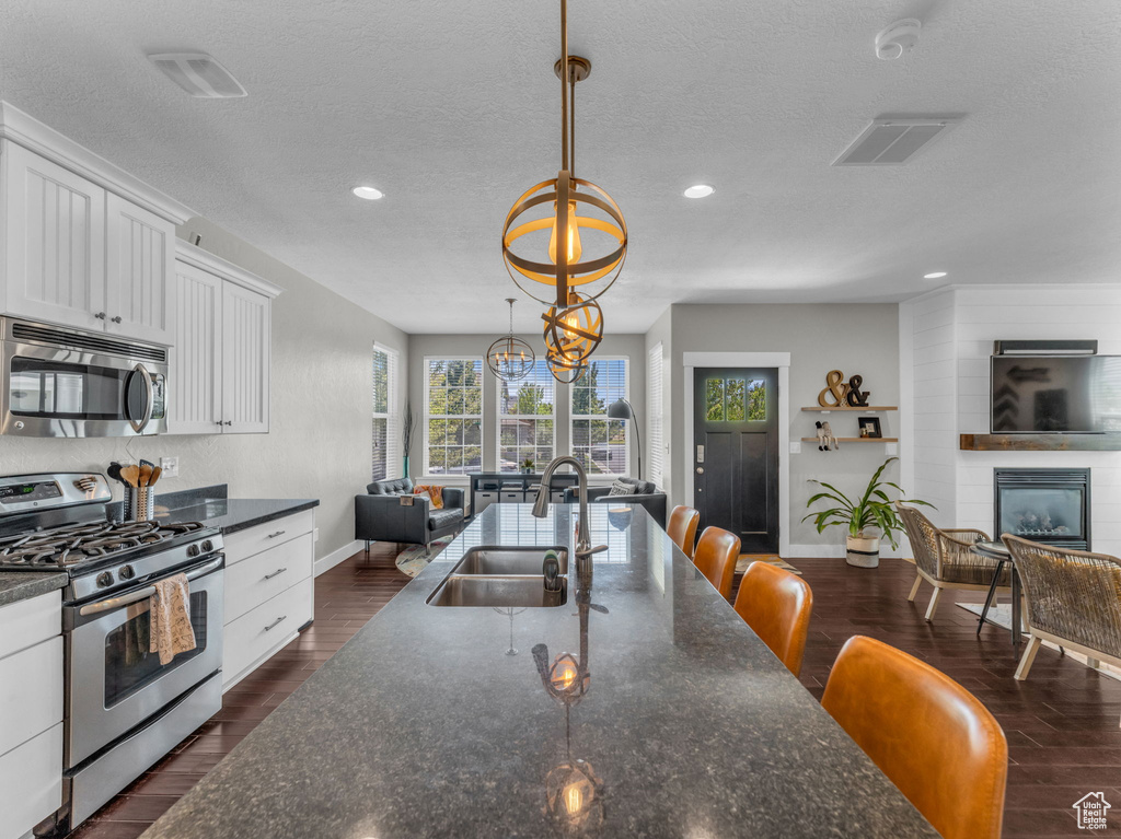 Kitchen featuring appliances with stainless steel finishes, white cabinetry, recessed lighting, a textured ceiling, and open floor plan