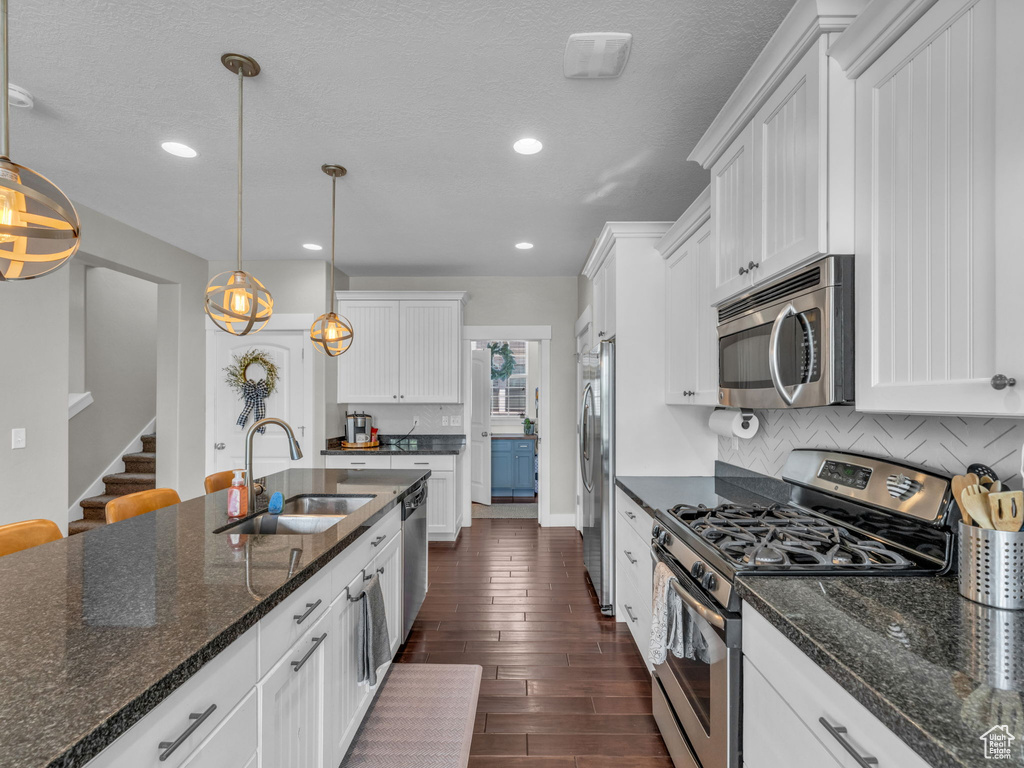 Kitchen featuring stainless steel appliances, white cabinets, dark wood-style flooring, decorative backsplash, and recessed lighting