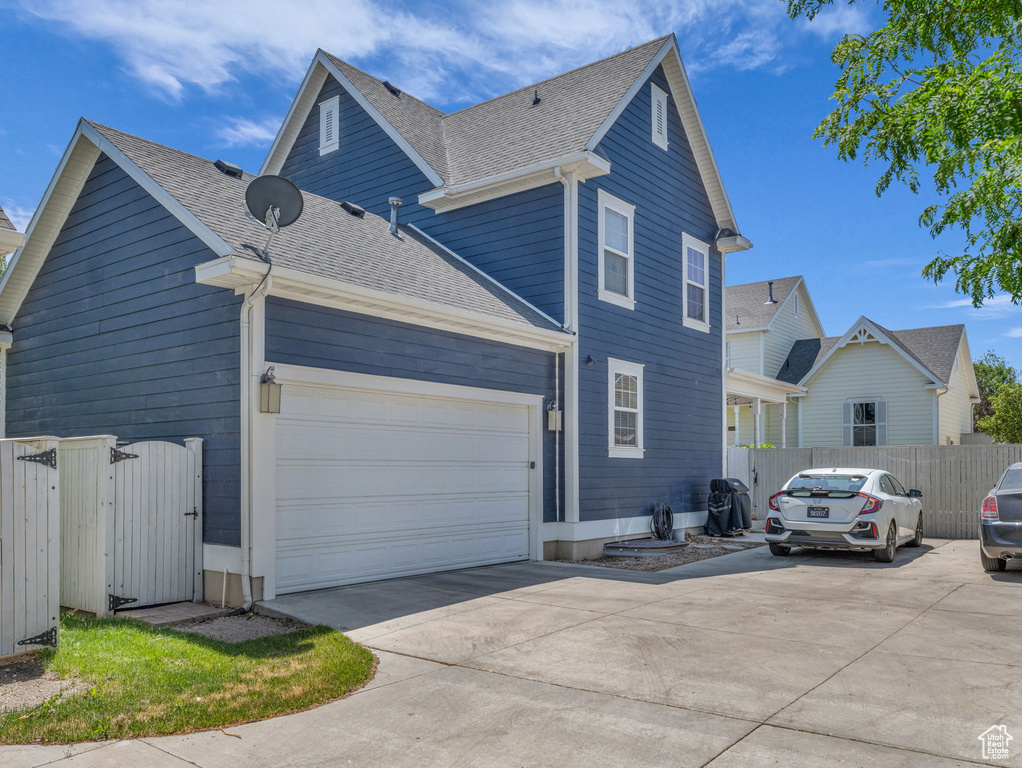 View of side of home featuring driveway and a shingled roof