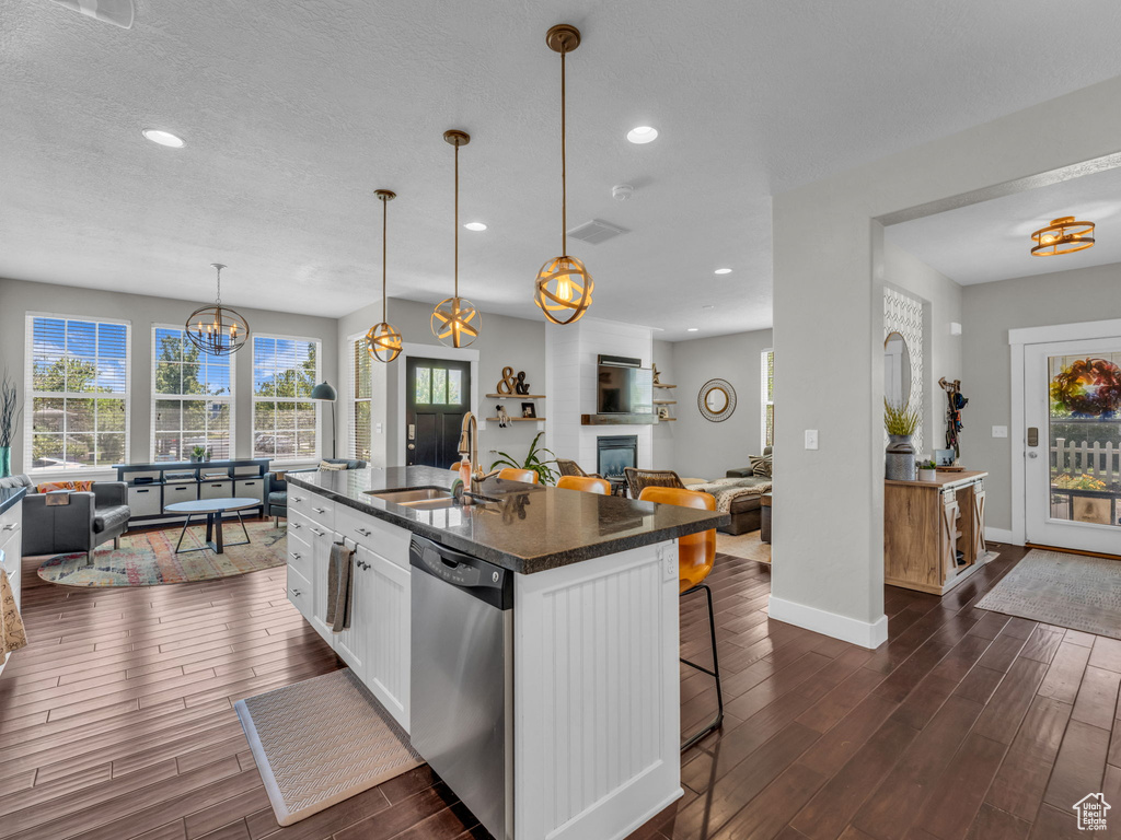Kitchen with dishwasher, dark wood finished floors, a kitchen breakfast bar, white cabinetry, and open floor plan