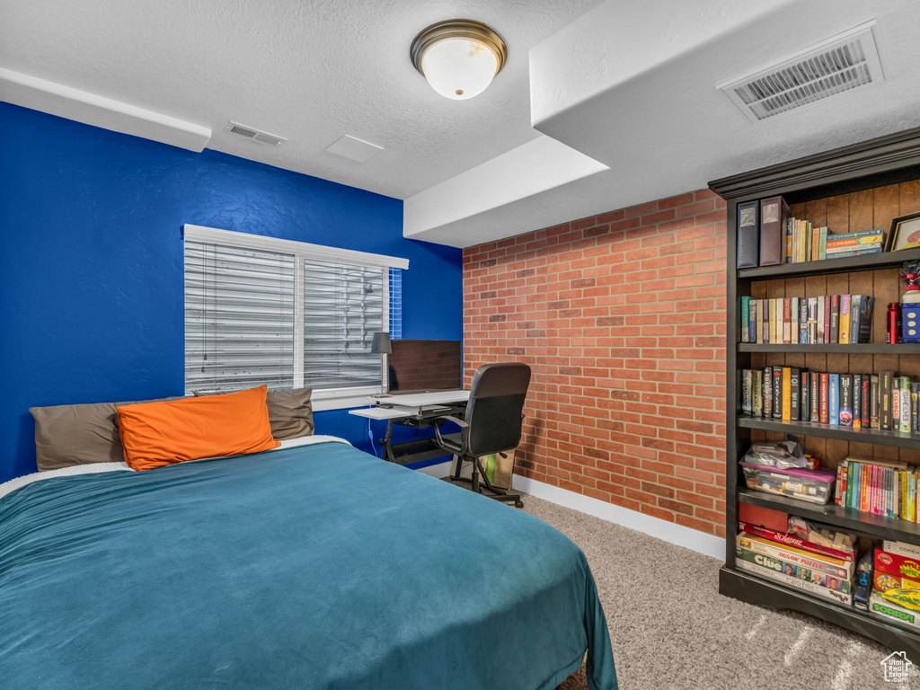 Carpeted bedroom with brick wall and a textured ceiling