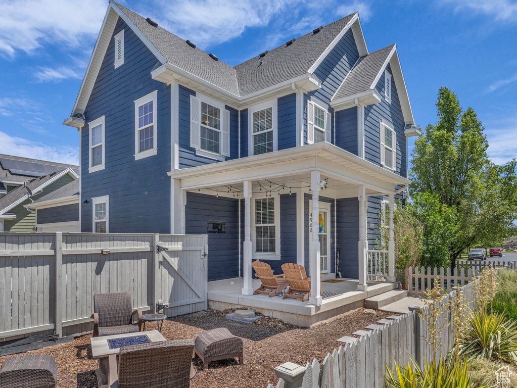 View of front of house with a gate, an outdoor fire pit, a porch, and roof with shingles