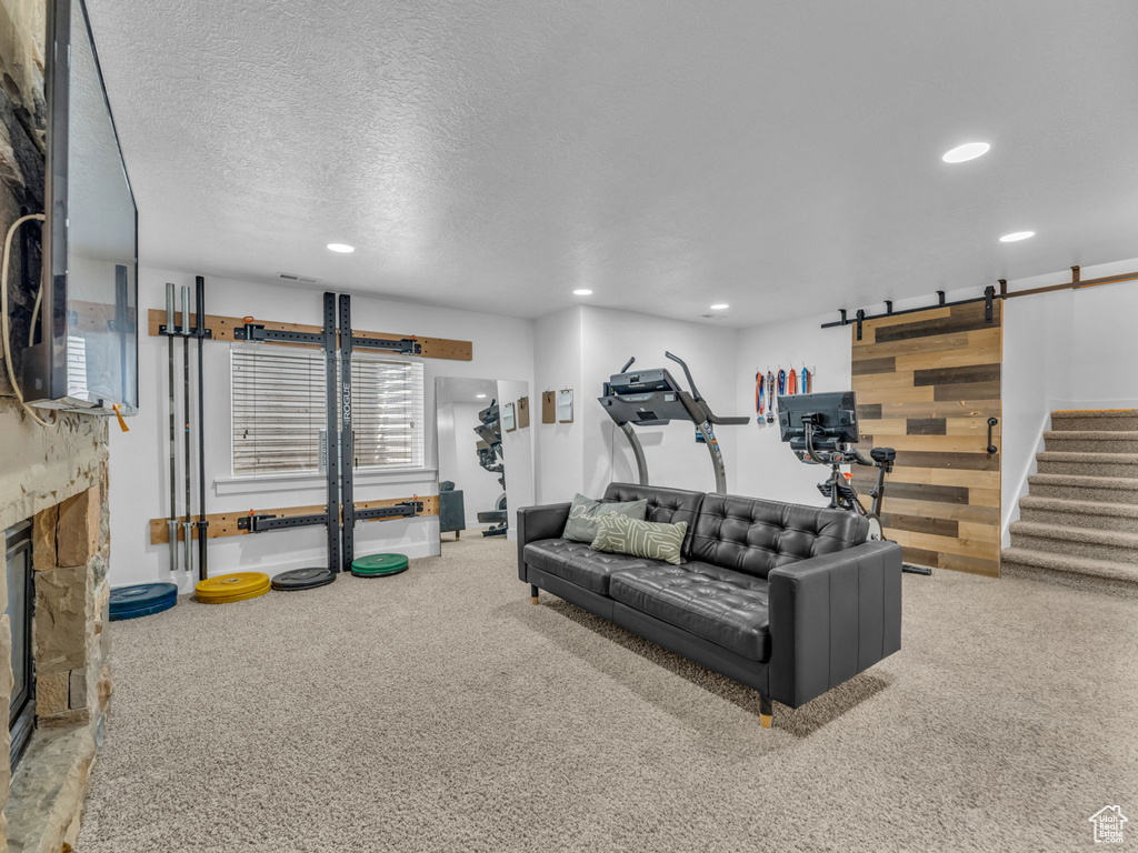 Carpeted living room with a barn door, recessed lighting, a fireplace, and a textured ceiling