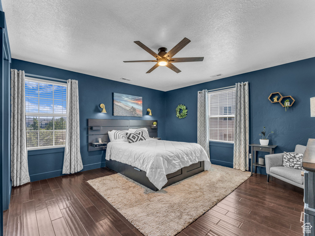 Bedroom featuring multiple windows, a textured ceiling, wood finished floors, and ceiling fan