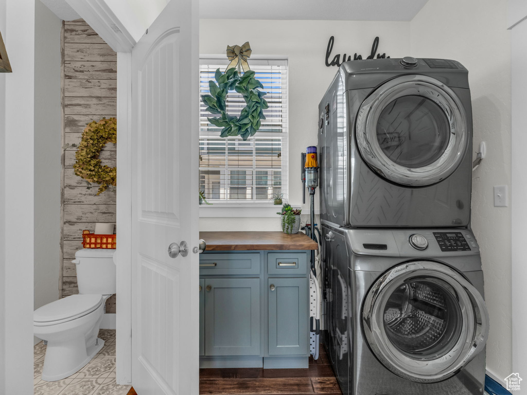Laundry room featuring estacked washer and dryer and wood walls
