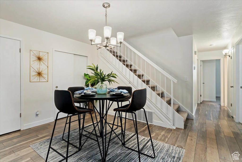 Dining room featuring stairway, hardwood / wood-style flooring, and a chandelier