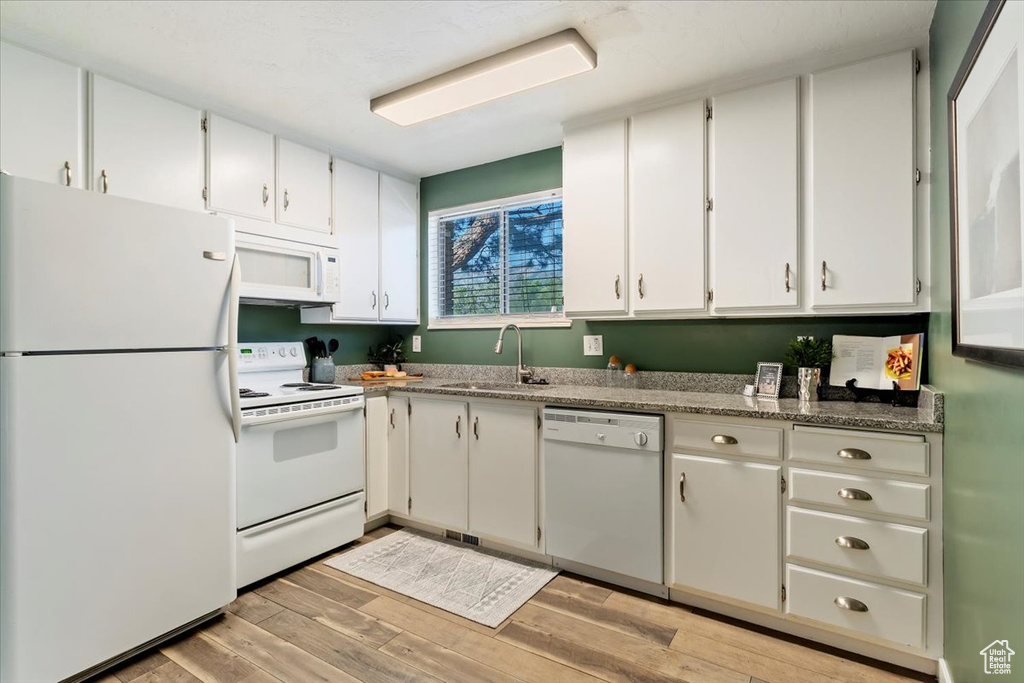 Kitchen featuring white appliances, light wood finished floors, and white cabinetry