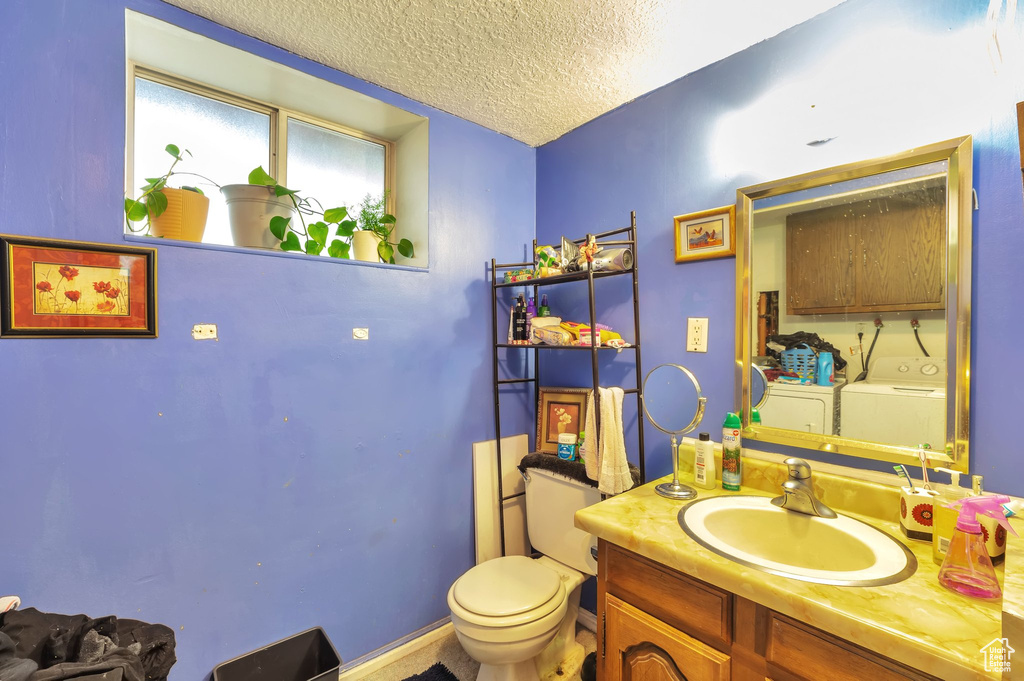 Bathroom featuring washer and dryer, a textured ceiling, and vanity