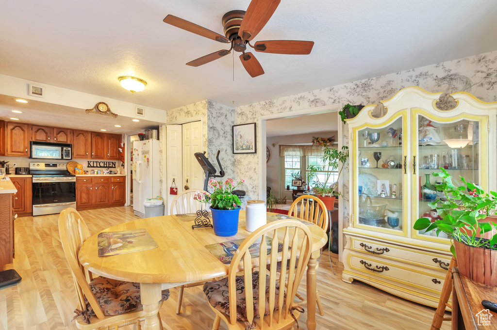 Dining space featuring wallpapered walls, ceiling fan, and light wood finished floors