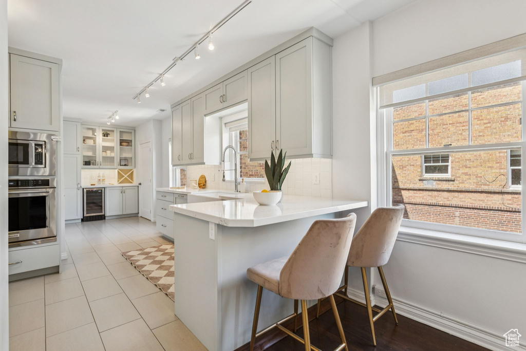 Kitchen featuring appliances with stainless steel finishes, wine cooler, tasteful backsplash, a breakfast bar area, and a peninsula