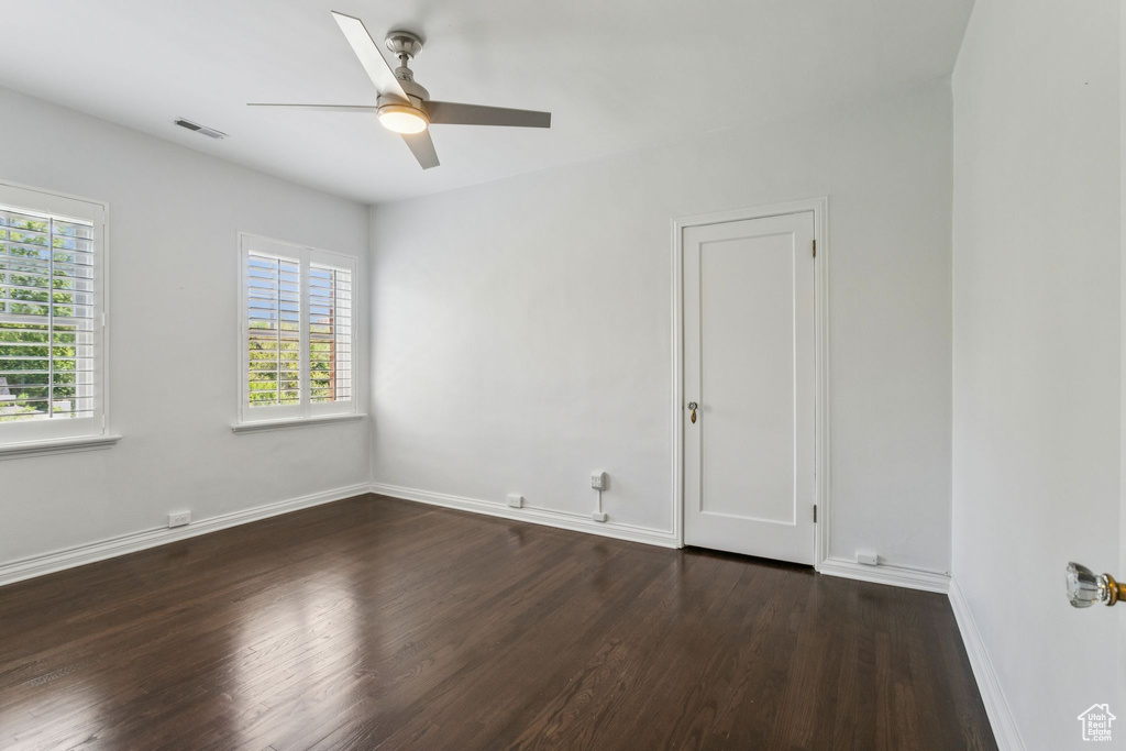 Unfurnished room with dark wood finished floors, healthy amount of natural light, and a ceiling fan
