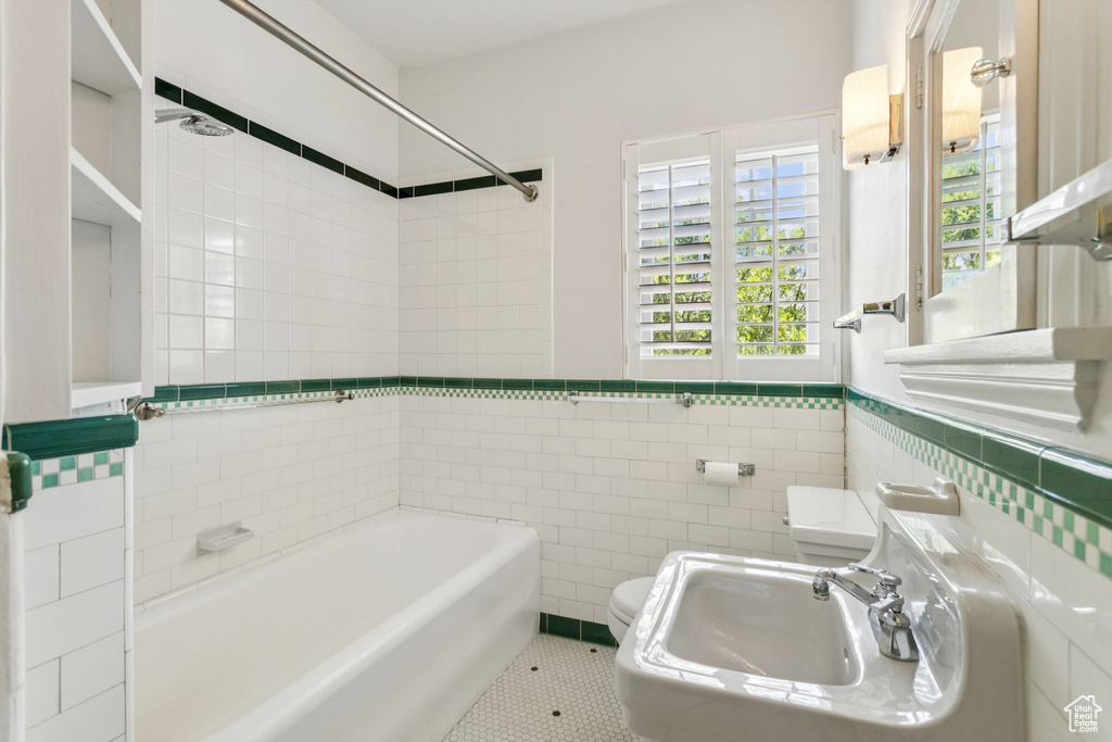 Full bath featuring tile walls, tile patterned flooring, shower / tub combination, and a wainscoted wall