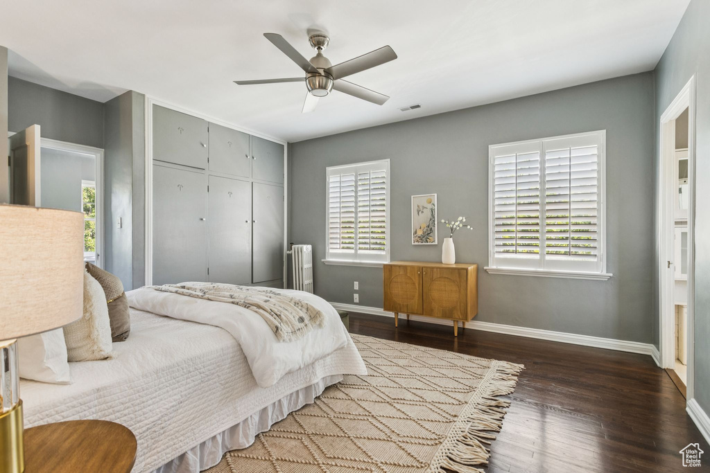Bedroom with wood finished floors, a closet, radiator heating unit, and ceiling fan