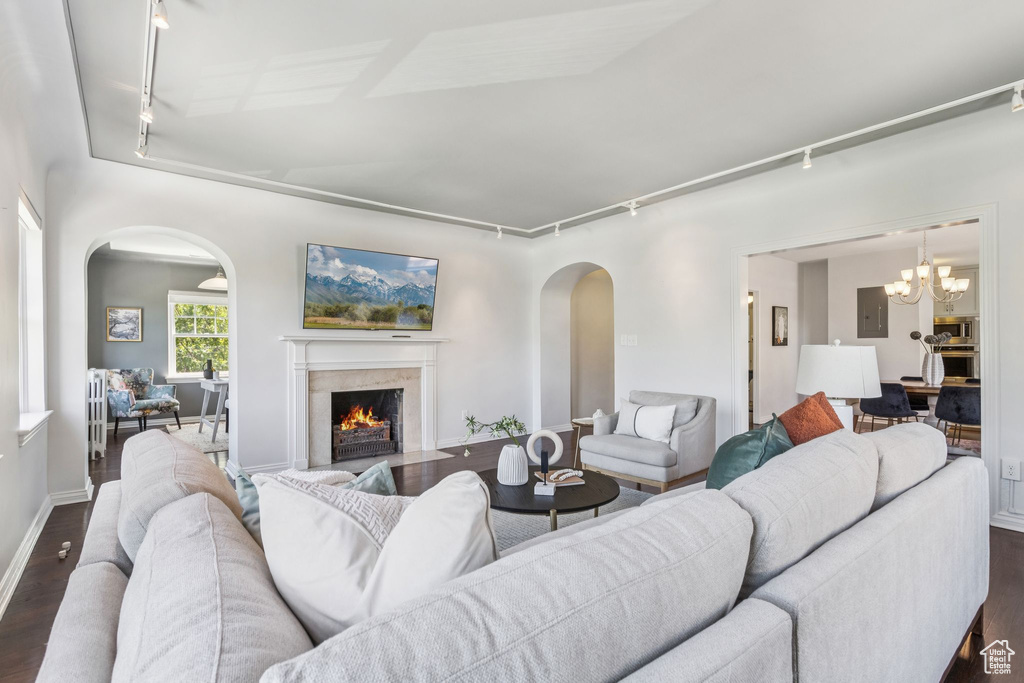 Living area with rail lighting, arched walkways, and dark wood finished floors