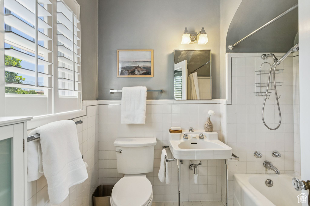 Bathroom featuring  shower combination, tile walls, and a wainscoted wall
