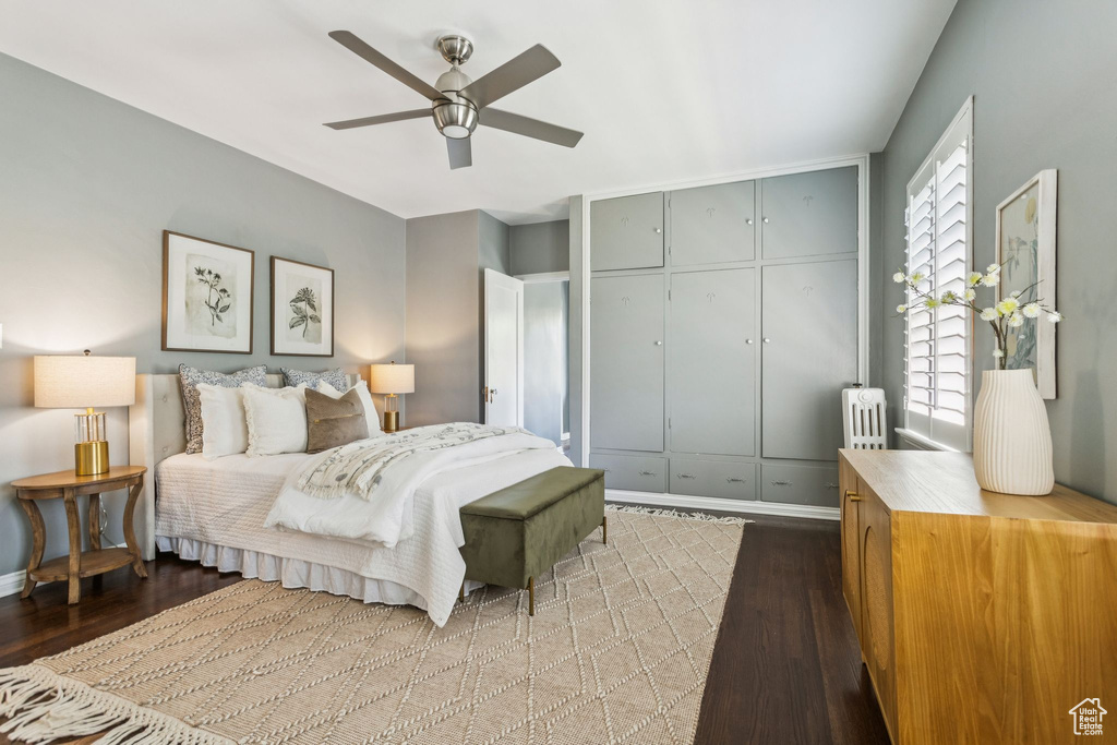 Bedroom with radiator heating unit, light wood-style flooring, ceiling fan, and a closet