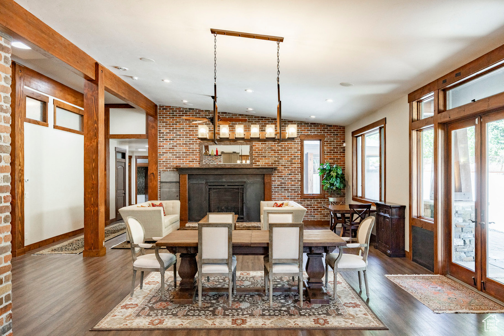 Dining space with brick wall, dark wood finished floors, a fireplace, and recessed lighting