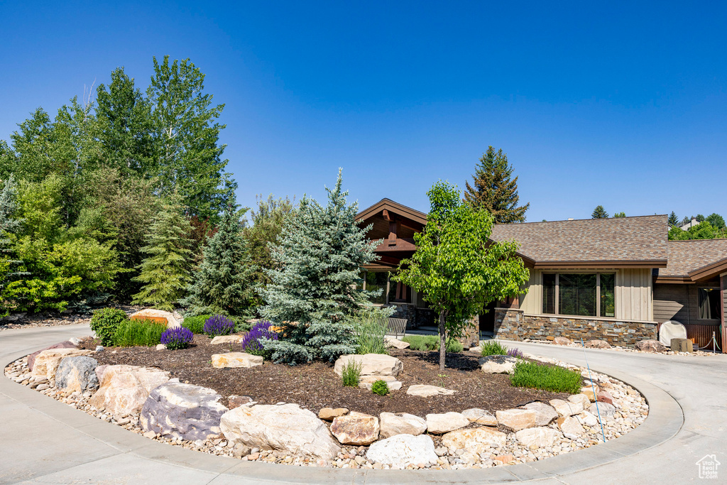 View of front facade featuring a shingled roof and stone siding