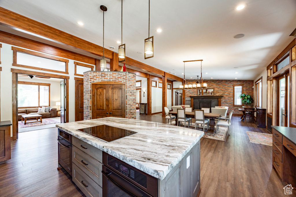 Kitchen featuring open floor plan, black appliances, plenty of natural light, brick wall, and recessed lighting